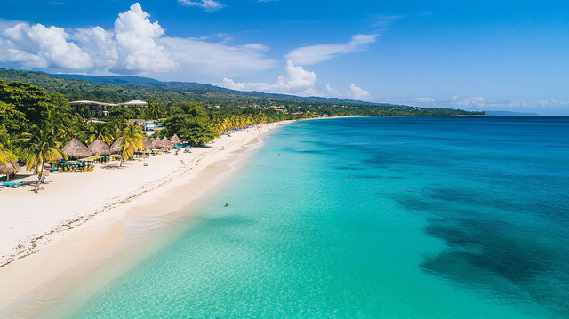 Aerial view of a white-sand beach in Puerto Plata lined with palm trees and thatched umbrellas beside turquoise water