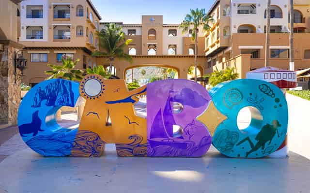Large painted CABO letters decorated with whales, divers and sailboats on a plaza at the Cabo San Lucas marina