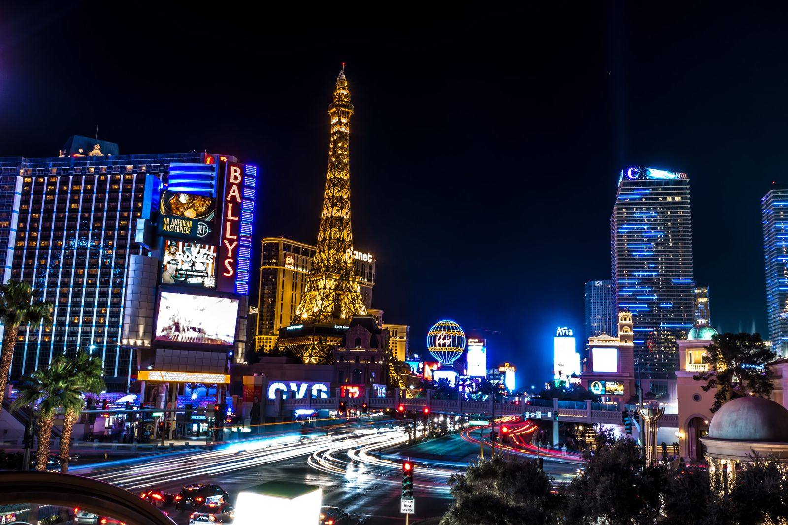 The Las Vegas Strip at night with lit hotel towers, an Eiffel Tower replica and light trails from traffic