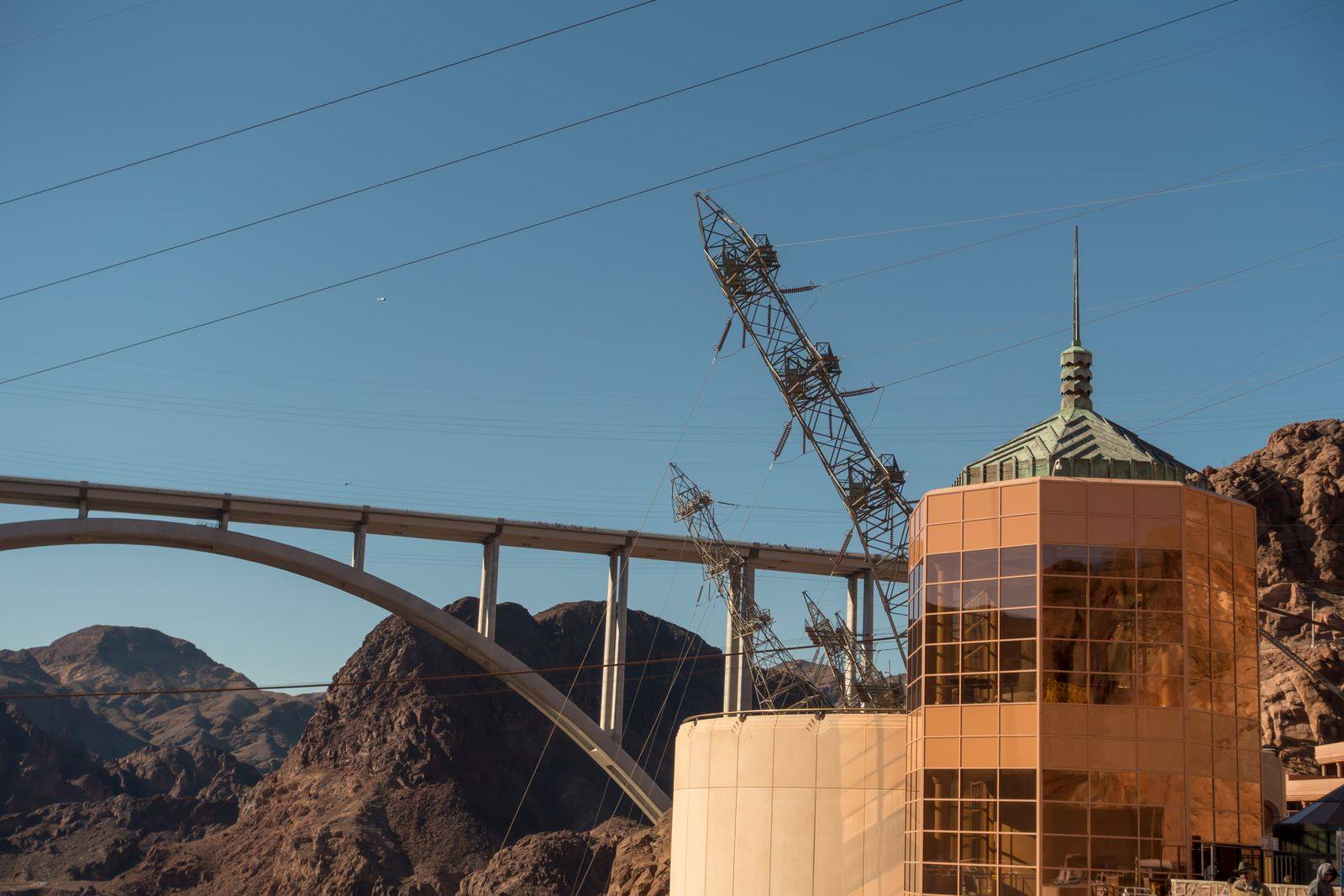 Hoover Dam intake tower and power lines in front of the arched bypass bridge and rocky desert hills
