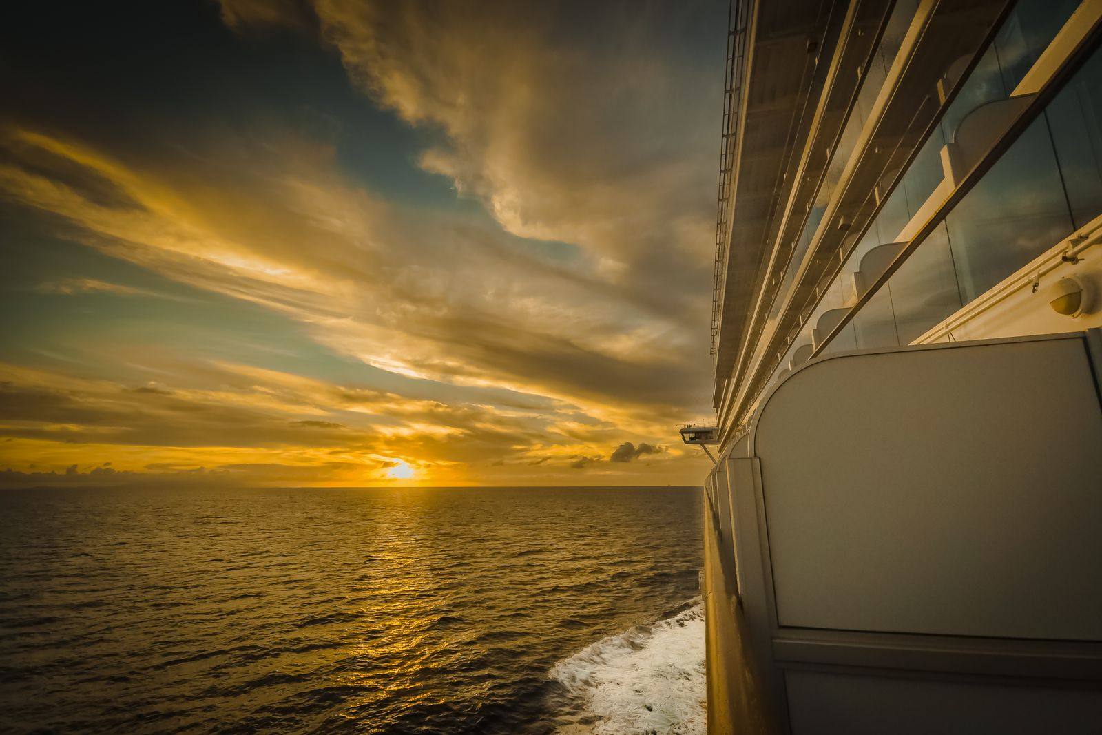 Golden sunset over the open sea, seen from the side of a cruise ship